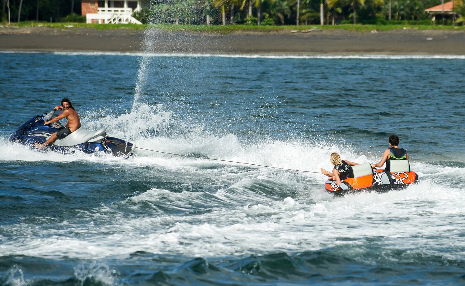 Jet ski towing riders on a tube from the Playgrounds catamaran, Tamarindo, Costa Rica