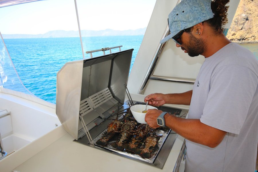 Crew grilling fresh lobster aboard the Playgrounds catamaran, Tamarindo, Costa Rica