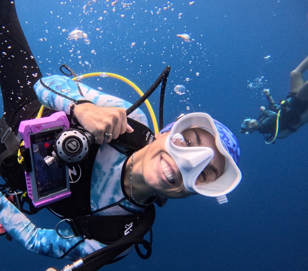 Camille Segonne, PADI OWSI and MSDT scuba instructor, smiling at the camera underwater