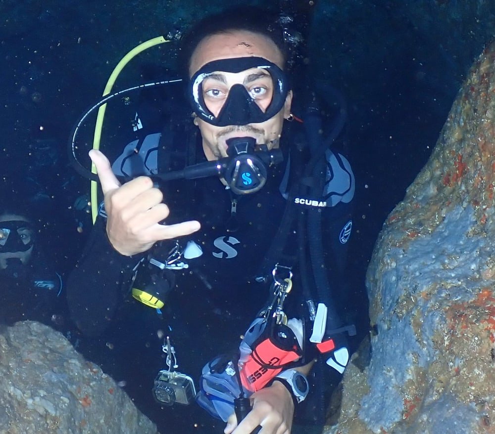 Julien Escales, PADI OWSI scuba instructor, making a shaka sign in an underwater cave